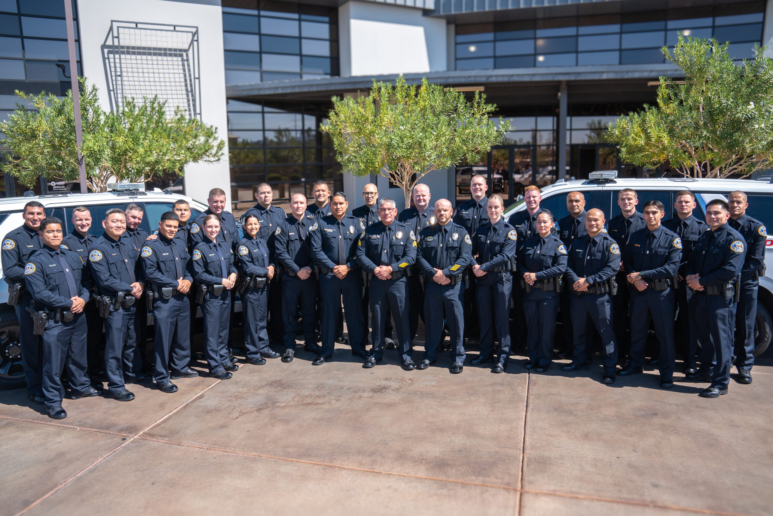 Henderson Police Academy graduates and officers pose together in uniform outside the police station.